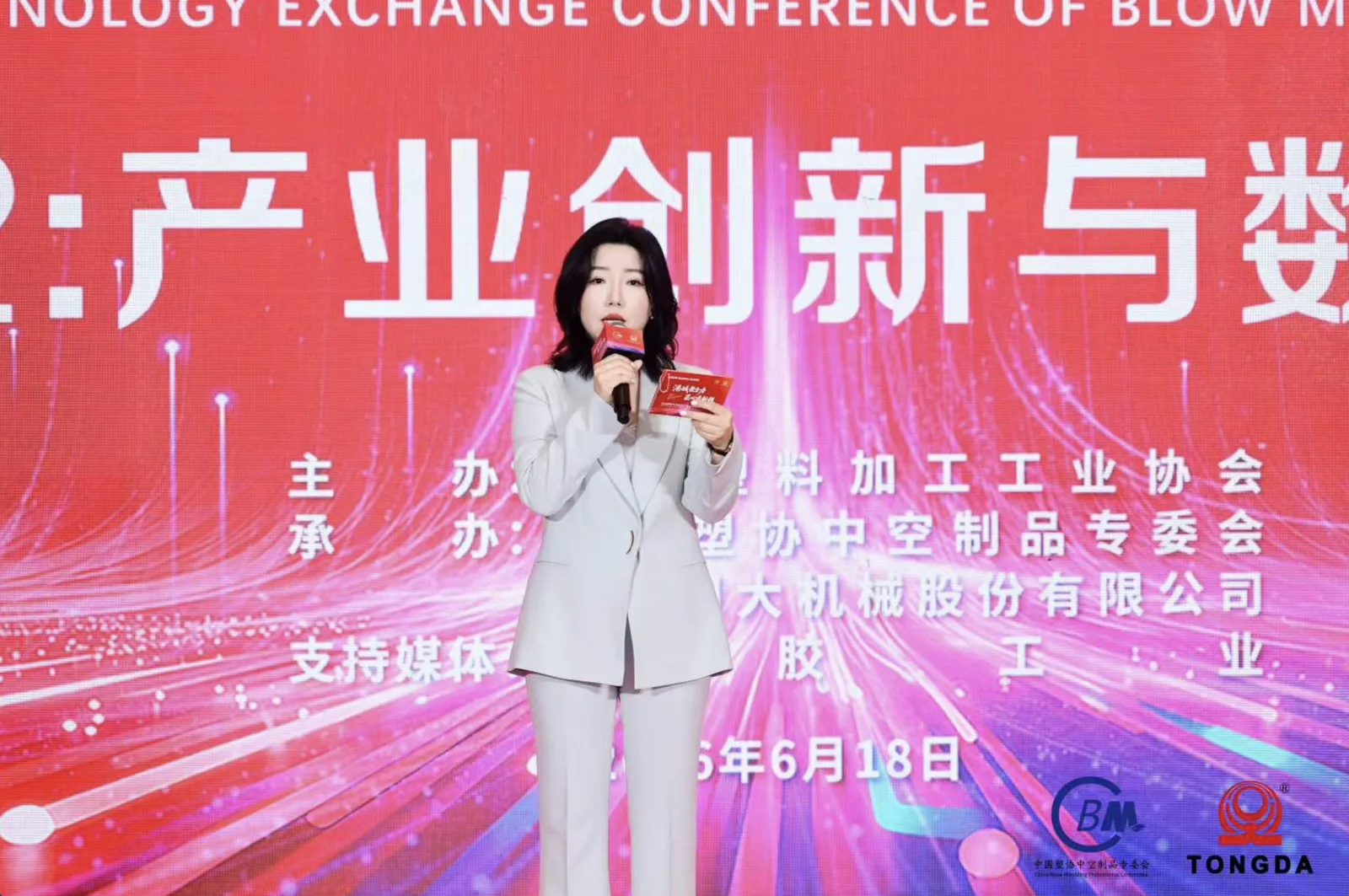 Eileen Yu выступает на сцене на конференции по обмену технологиями в отрасли выдувного формования